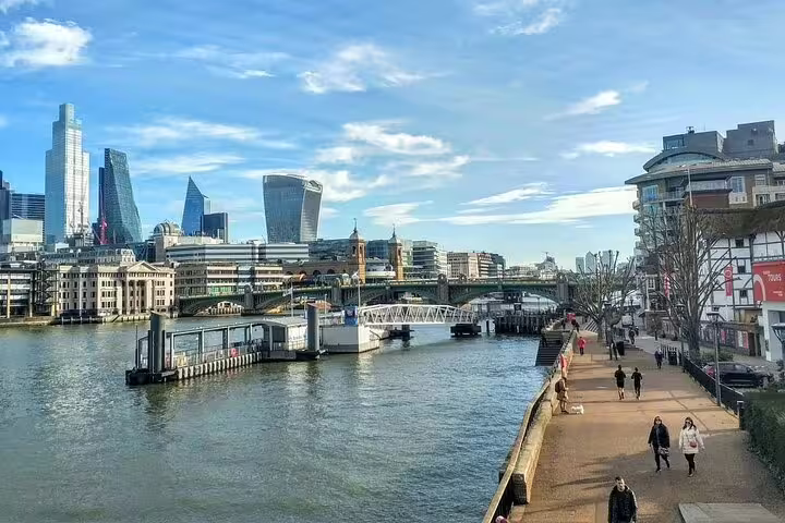 Southwark riverside walkway along the Thames with London city skyline and Southwark Bridge in background
