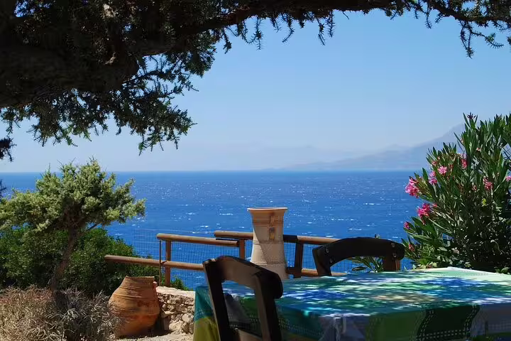 Charming outdoor dining area overlooking the vibrant blue sea in Southwest Crete, ideal for a hiking tour rest stop.