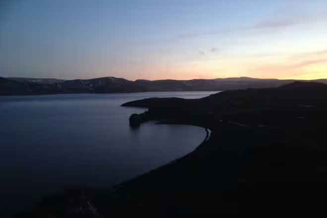 Aerial view of a calm bay at sunset in Southwest Iceland with rolling hills and twilight sky