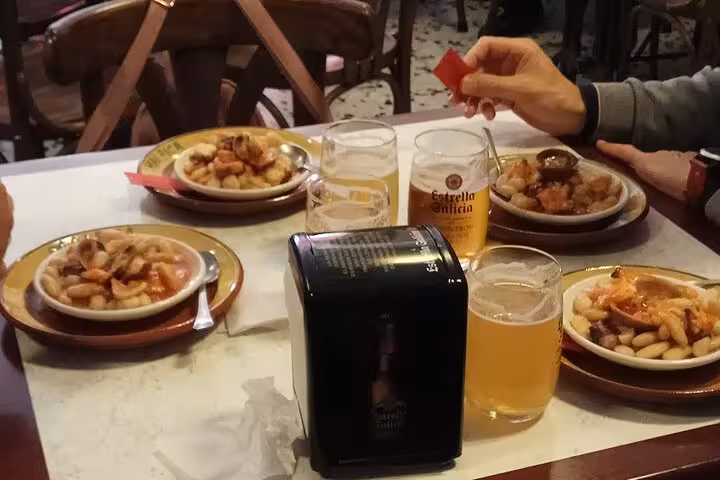 Plates of traditional Spanish beans with beer glasses in Santiago Old Town tapas experience.
