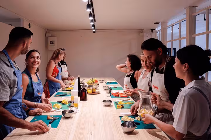 Participants enjoy hands-on Spanish tapas cooking class in Barcelona, preparing fresh ingredients together.