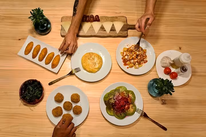 Authentic Spanish tapas including tortilla, croquettes, patatas bravas, and cheese platter at a cooking class in Barcelona.