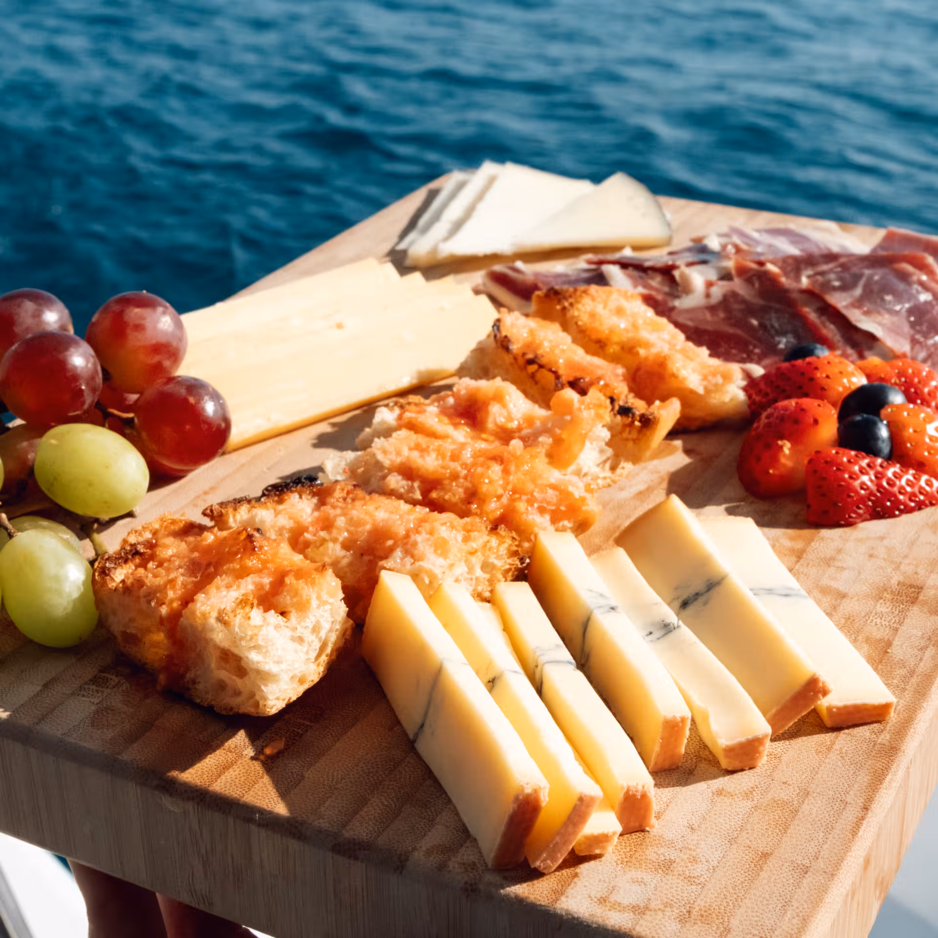 Spanish tapas board with cheese, jamón, fruit and tomato bread on a private luxury catamaran in Barcelona