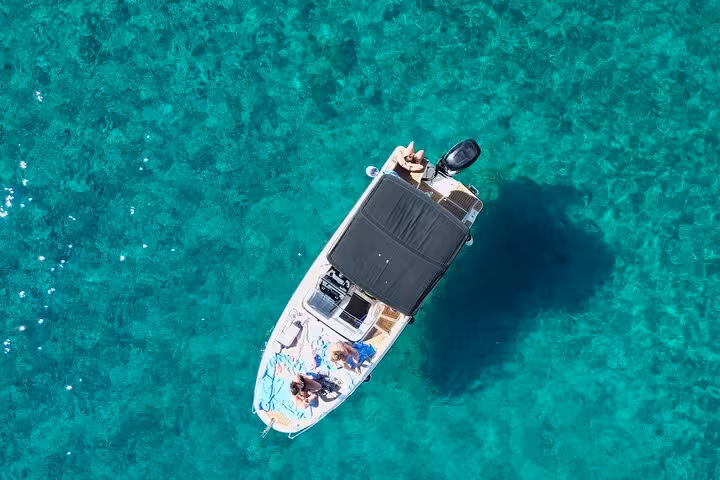 Private speedboat anchored in crystal-clear Adriatic water near Paklinski Islands on Hvar day tour