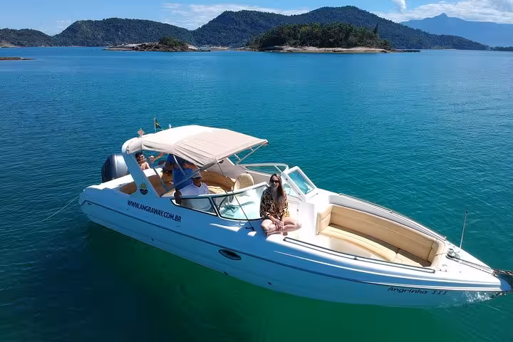 Tourists enjoying a scenic speedboat ride on Lagoa Azul with stunning views of lush islands and turquoise waters.