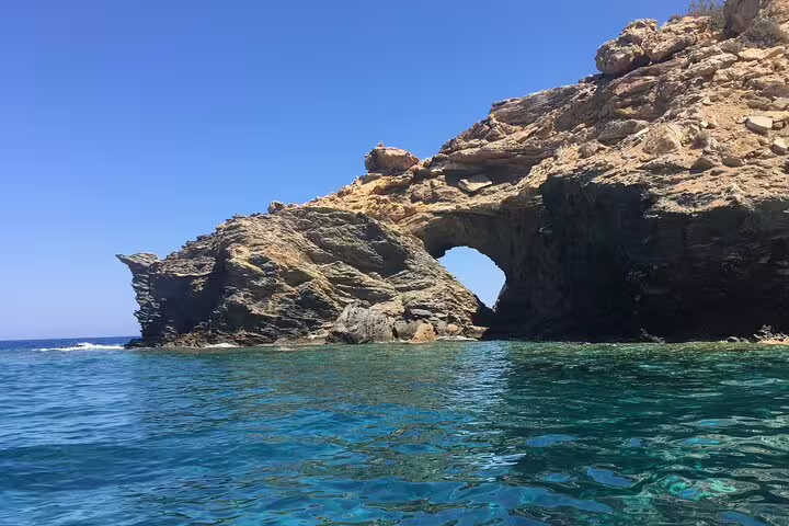 Stunning rock formation with a natural arch over bright blue sea, ideal for exploring on a half-day speedboat tour.