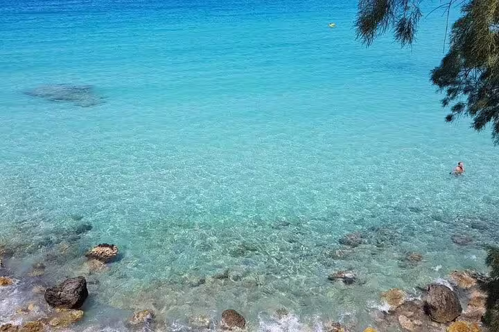 Crystal-clear turquoise waters ideal for swimming and snorkeling on a sun-kissed beach, perfect for a half-day tour.