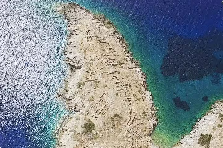 Aerial view of a historic coastal ruin surrounded by clear blue waters, ideal for exploration on a speedboat tour.
