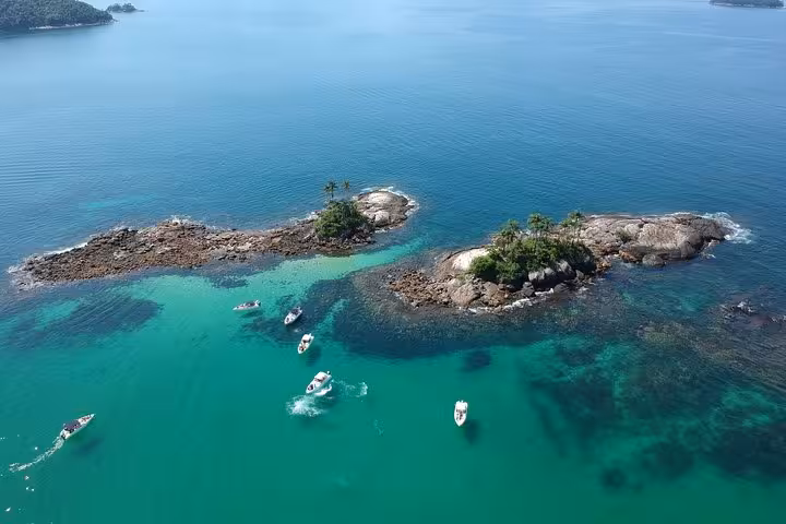 Aerial view of speedboats exploring turquoise waters around lush, rocky islets on a shared Paradise Island tour.