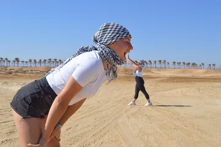 Tourists posing in Marsa Alam desert during Spider car buggy safari and camel ride adventure excursion