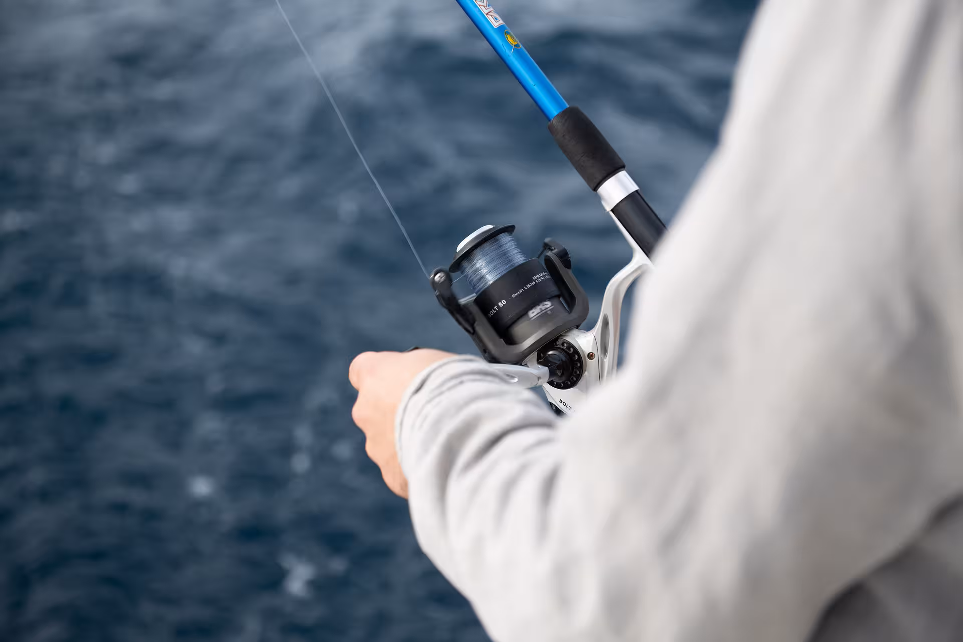 Close-up of spinning reel and rod over deep blue water on a Mediterranean fishing excursion and boat charter
