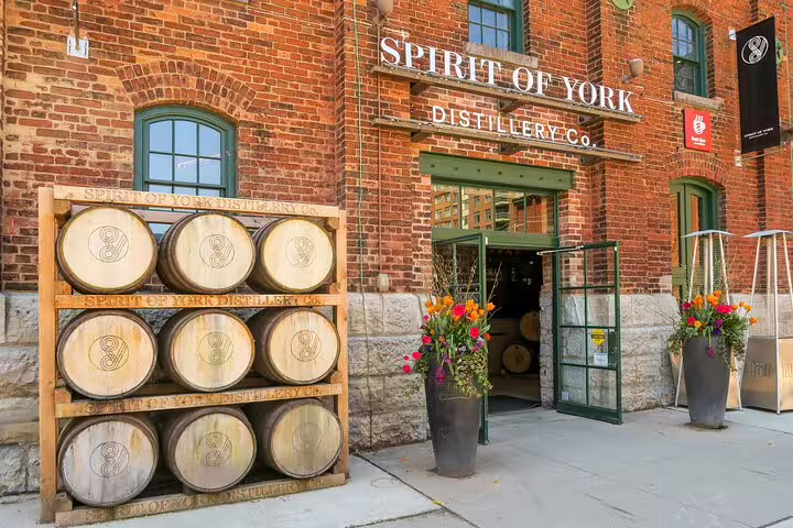 Spirit of York Distillery Co. brick building entrance with wooden whiskey barrels stacked outside in Toronto's Distillery District