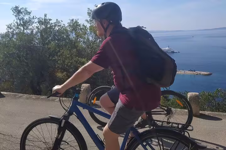 Cyclist on coastal road with Adriatic Sea view on Split City Bike Tour, guided bike ride with sea panorama