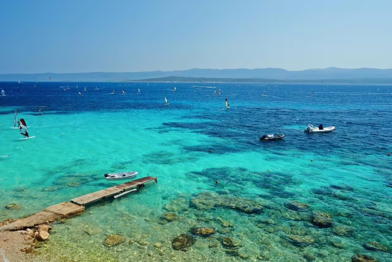 Turquoise Adriatic bay with boats and windsurfers, a swim stop on the Split to Dubrovnik cruise