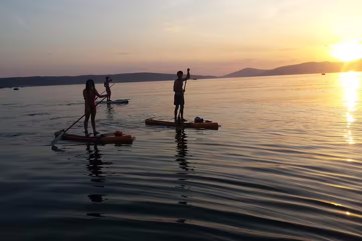 Split sunset stand up paddleboarding tour on calm Adriatic Sea, paddlers gliding toward golden horizon