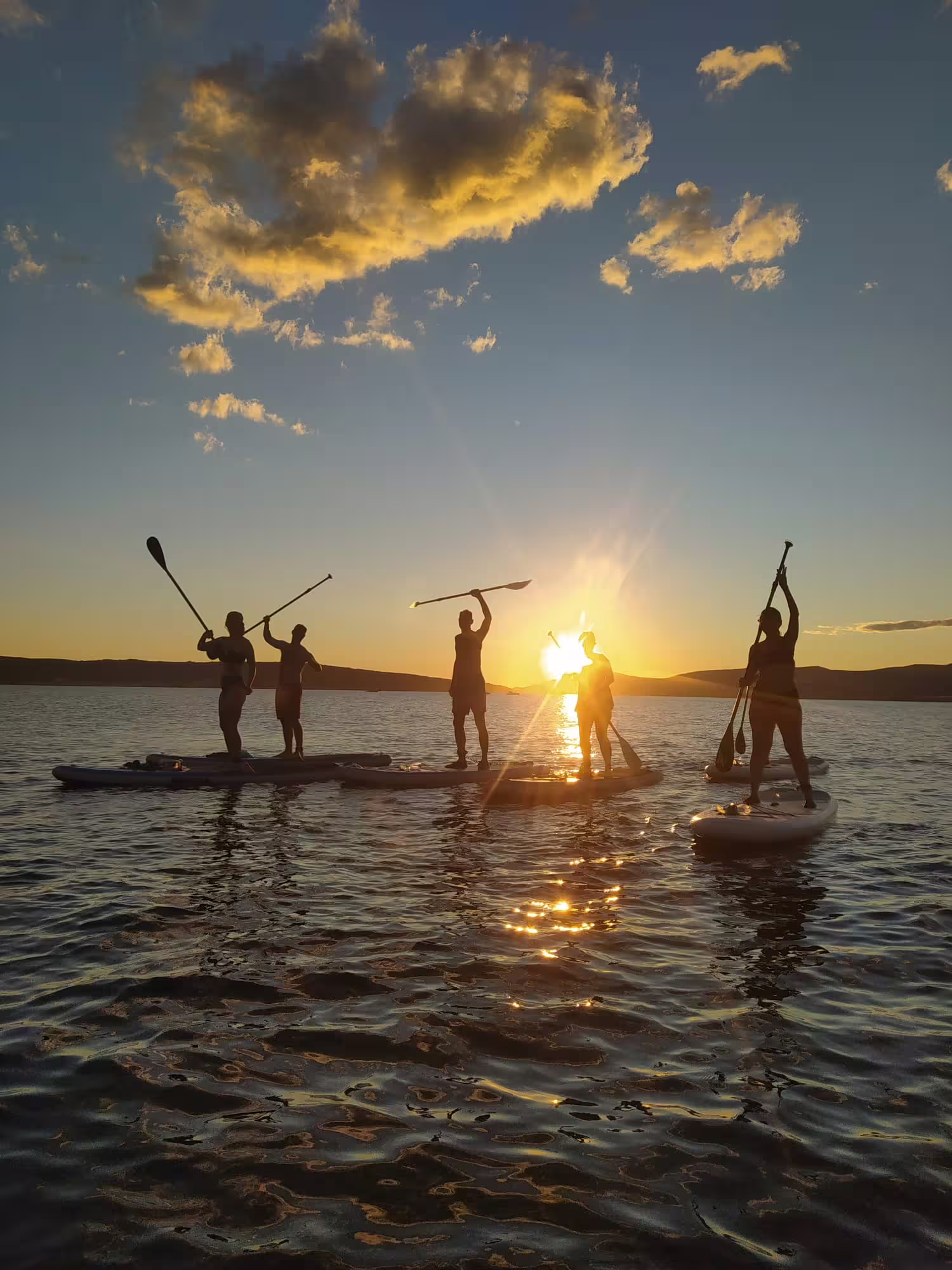 Group SUP at sunset near Split, Croatia, paddles raised on Adriatic waters, perfect for wine paddle tour