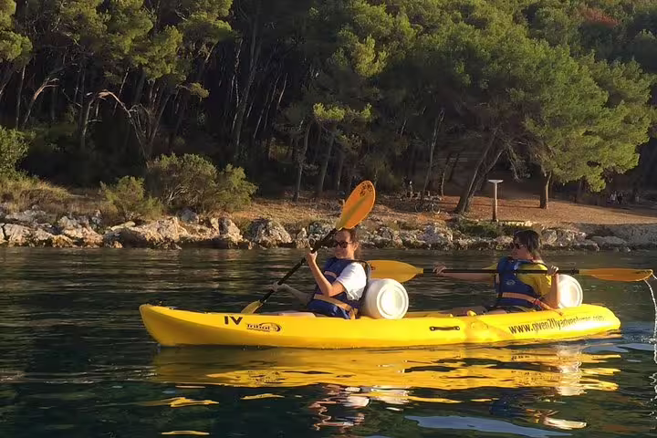 Tandem kayak near pine-lined shore on Split sea kayaking & snorkeling tour, calm Adriatic waters in Croatia