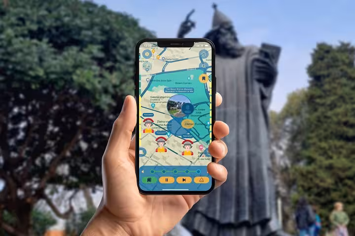 Hand holding smartphone with walking tour app near Gregory of Nin statue landmark on self-guided Split city tour