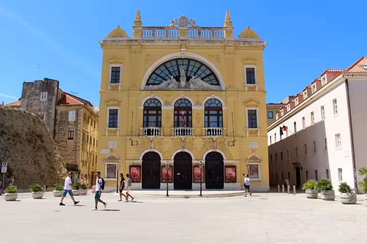 Yellow neoclassical Croatian National Theatre building in Split's Republic Square on a sunny day