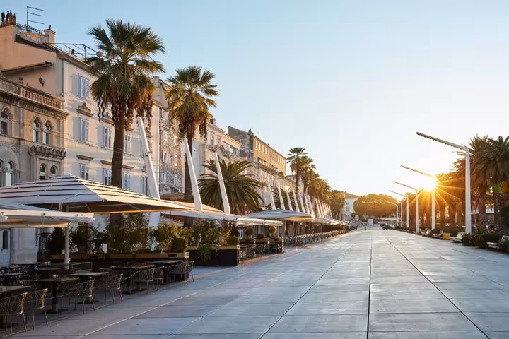Split waterfront promenade Riva at sunrise with palm trees and outdoor cafe terraces