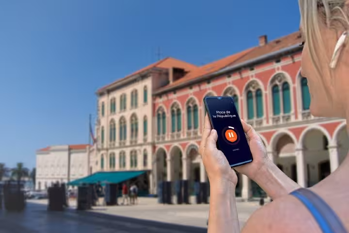 Tourist holding smartphone with audio tour app at Split's Republic Square historic building