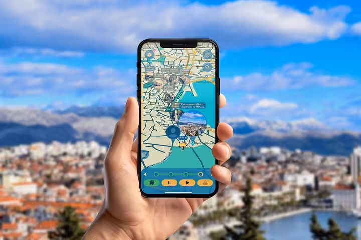Hand holding smartphone displaying Split self-guided walking tour app with interactive city map and scenic backdrop