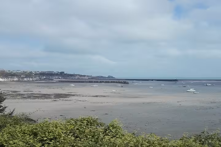 Low tide estuary view near St Malo with boats resting on sandy flats and coastal town in background