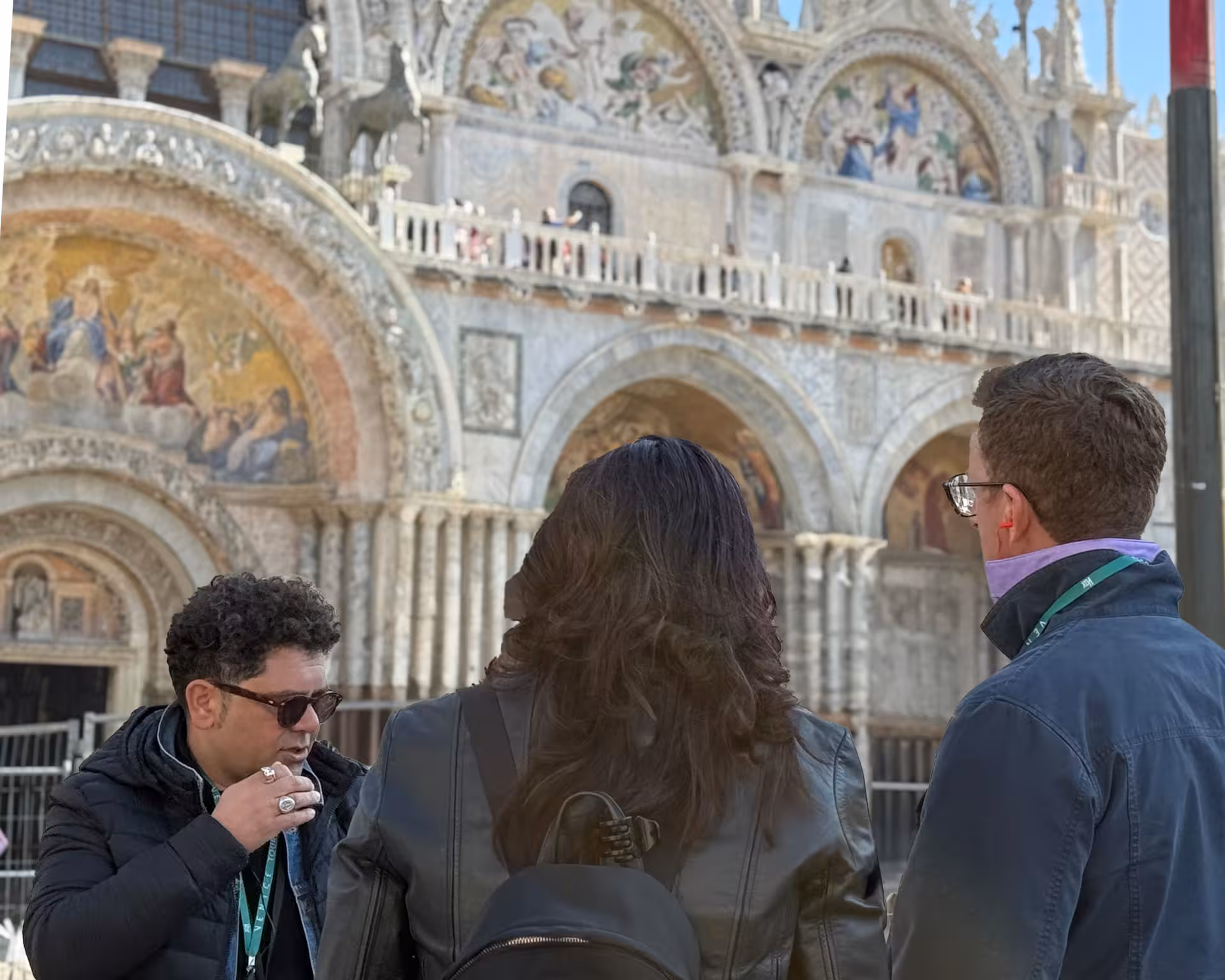 Tour group explores St. Mark's Basilica façade with a guide, emphasizing Venice's rich history and detailed mosaics.