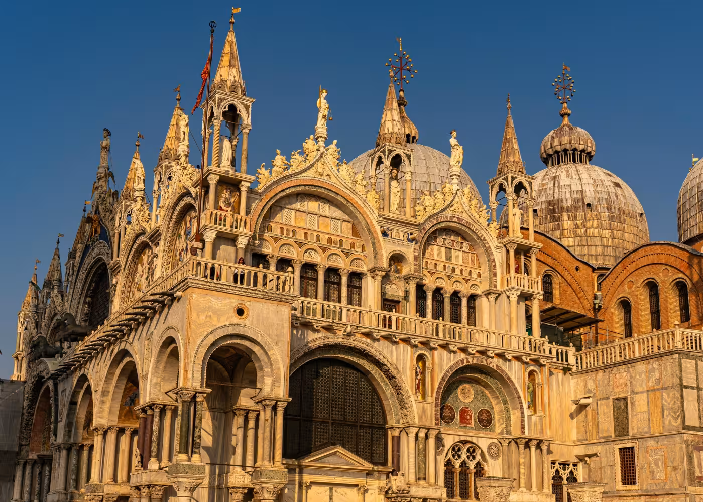 St Mark's Basilica in Venice, showcasing intricate Byzantine architecture and golden mosaics under a clear blue sky.