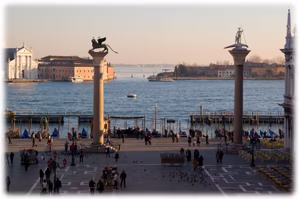 View of St Mark’s waterfront in Venice with twin columns, boats and strolling visitors on a 2-day private tour from Rome