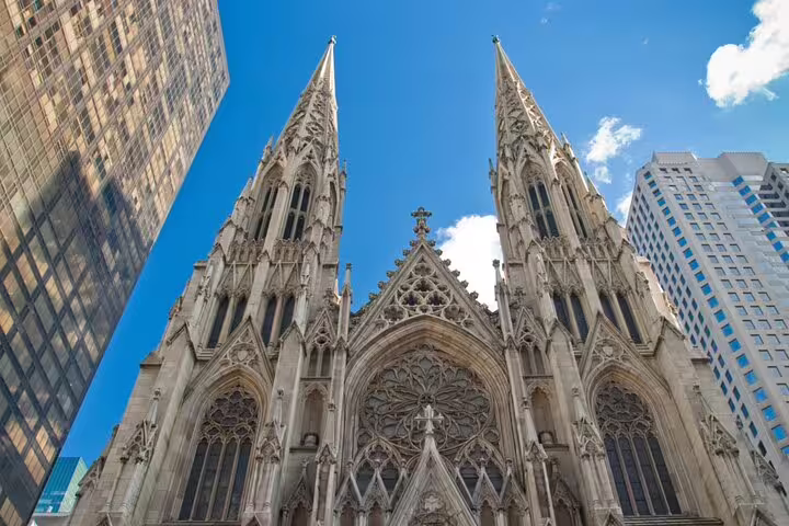 Gothic facade of St. Patrick's Cathedral with twin spires surrounded by Midtown Manhattan skyscrapers
