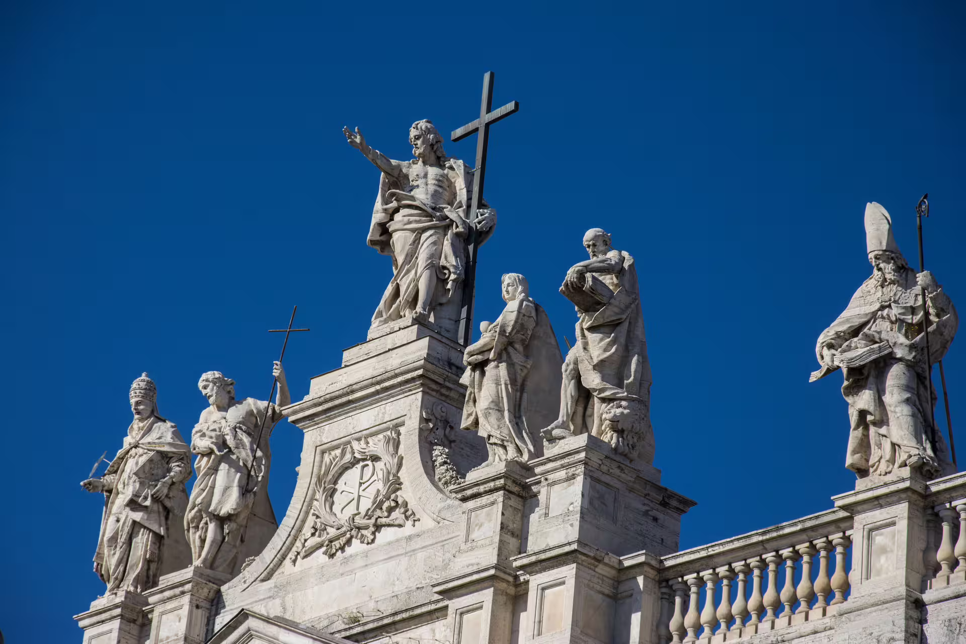 Close-up of apostles and saints statues atop St Peter’s Basilica under blue sky, detail from Christian Rome semi-private tour