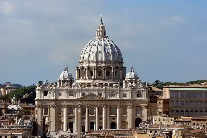Panoramic view of St. Peter's Basilica dome against a cloudy sky, capturing its iconic Renaissance architecture.