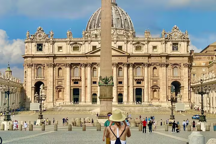 Tourists gather in St Peter's Square facing St Peter's Basilica and obelisk before an early morning VIP dome climb tour