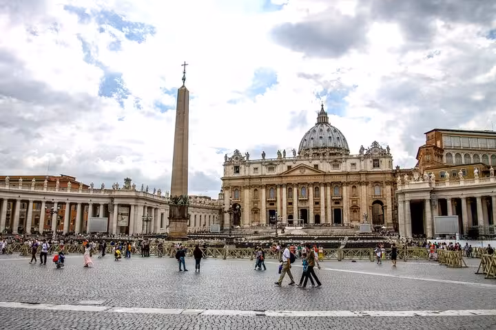 View of St. Peter's Basilica and Vatican Square bustling with tourists on a cloudy day, perfect for Vatican tours.