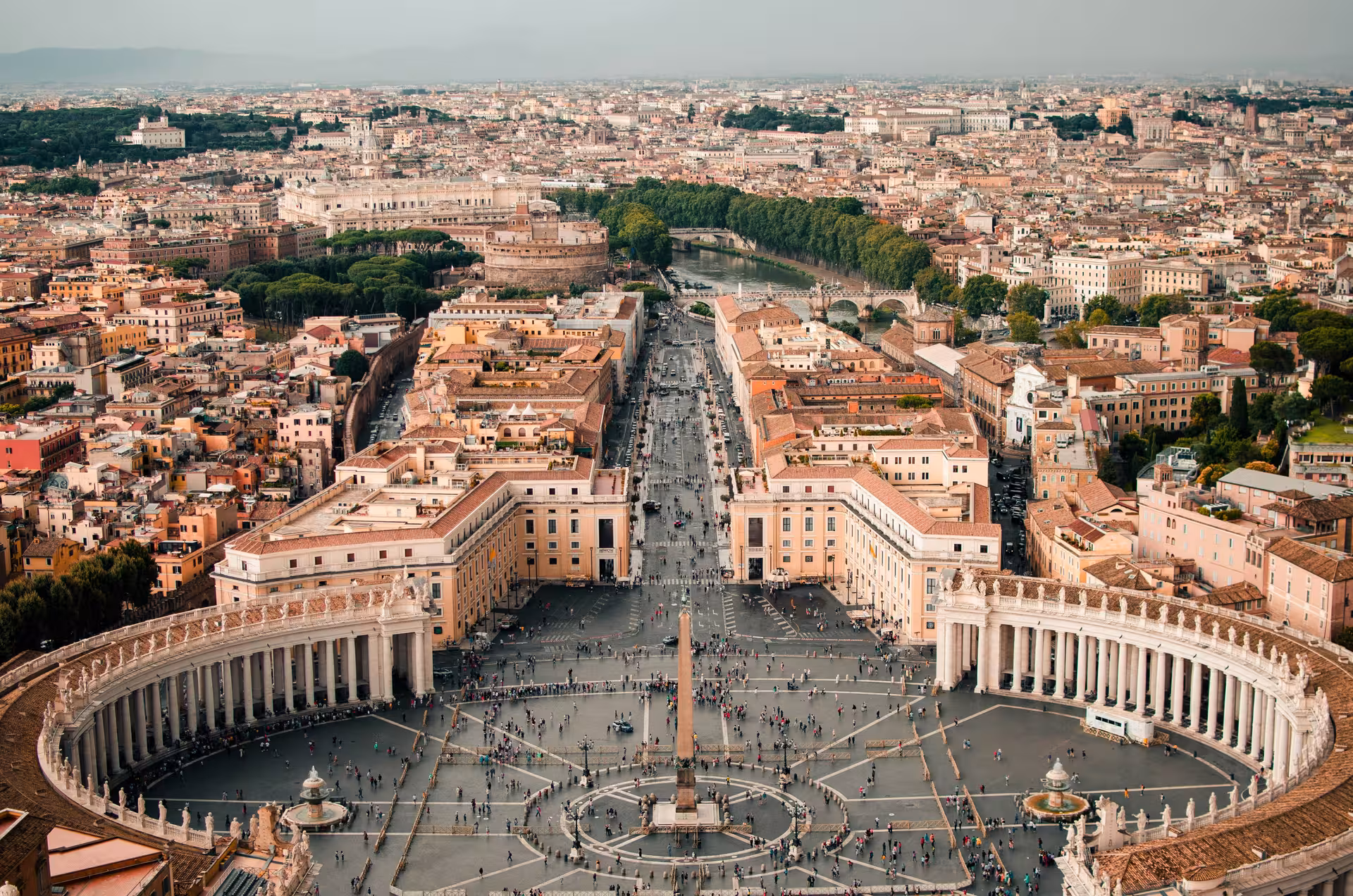 Aerial view of St. Peter's Square in Vatican City, showcasing its iconic colonnade and bustling tourist activity.