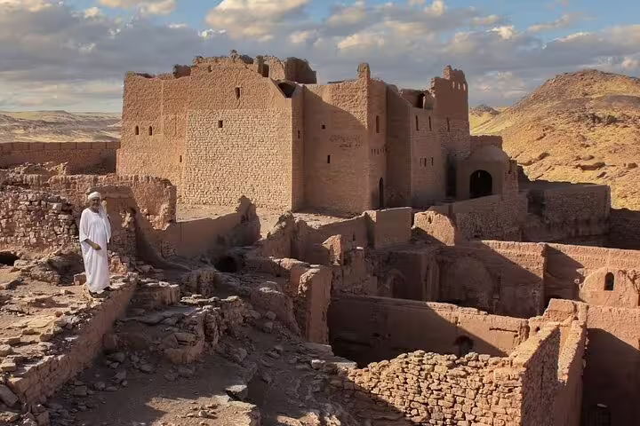 Panoramic view of St. Simeon Monastery ruins in Aswan desert with visitor, featured on guided monastery trip