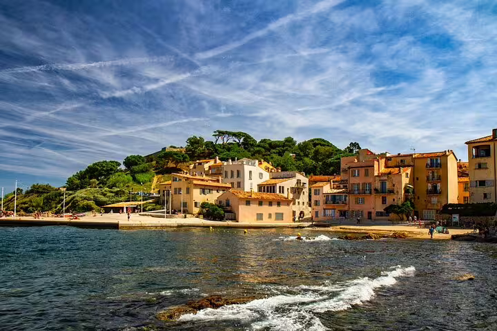 Colorful waterfront buildings of St Tropez along the turquoise Mediterranean coast under a blue sky