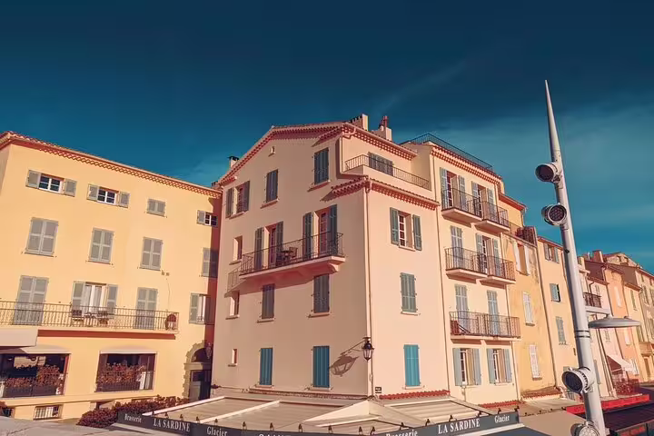 Colorful pastel buildings with shutters and balconies in St Tropez waterfront, clear blue sky