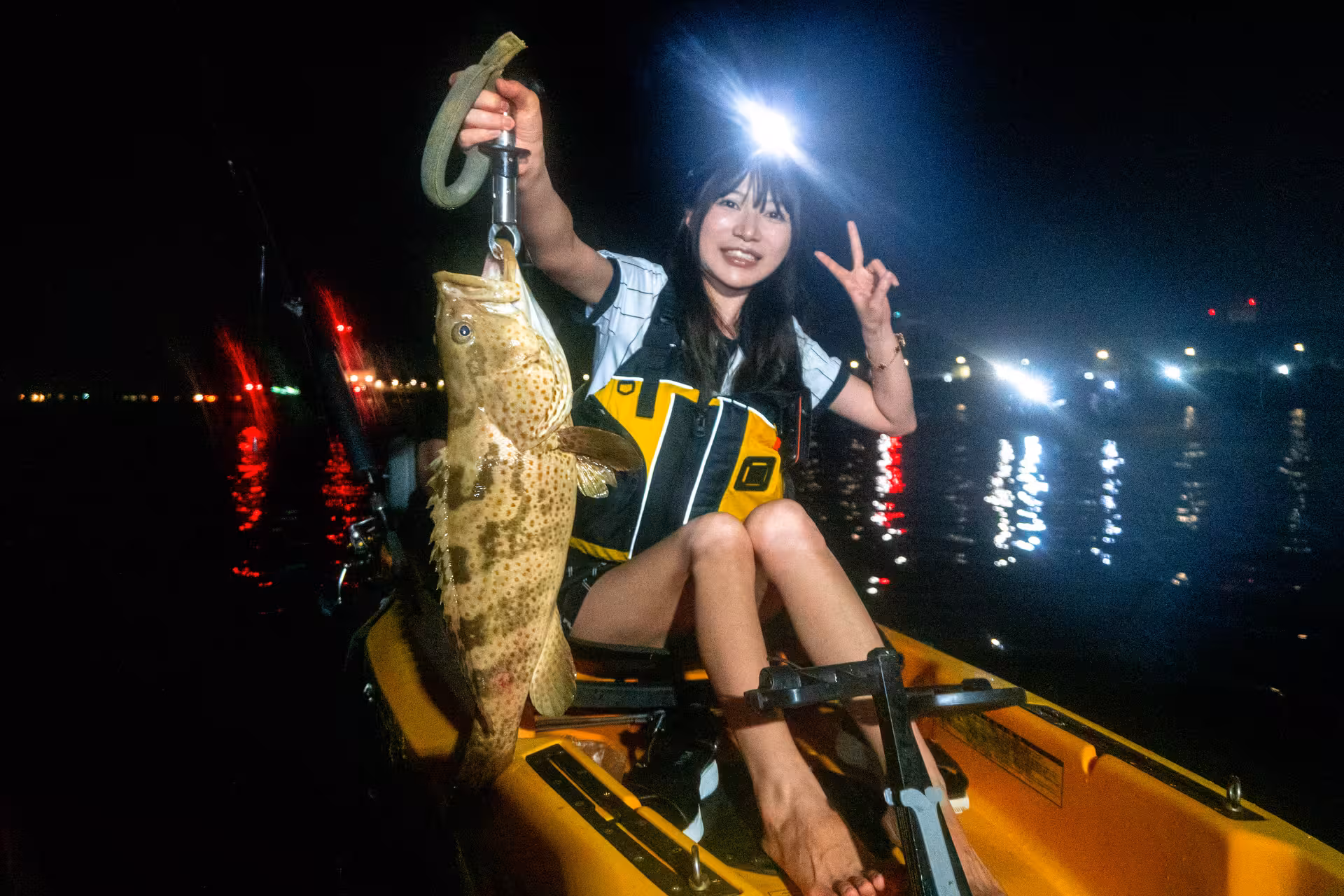 Kayaker proudly displays a large fish caught during a starry night fishing adventure at Pulau Ubin.