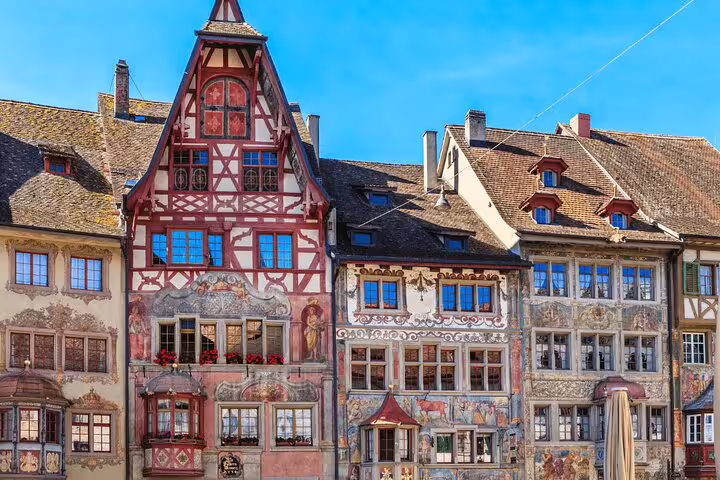 Charming medieval buildings with intricate frescoes in the picturesque town of Stein am Rhein against a bright blue sky.