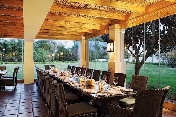 Elegant dining setup in a glass-walled Stellenbosch venue, offering a refined atmosphere for a private wine tour experience.