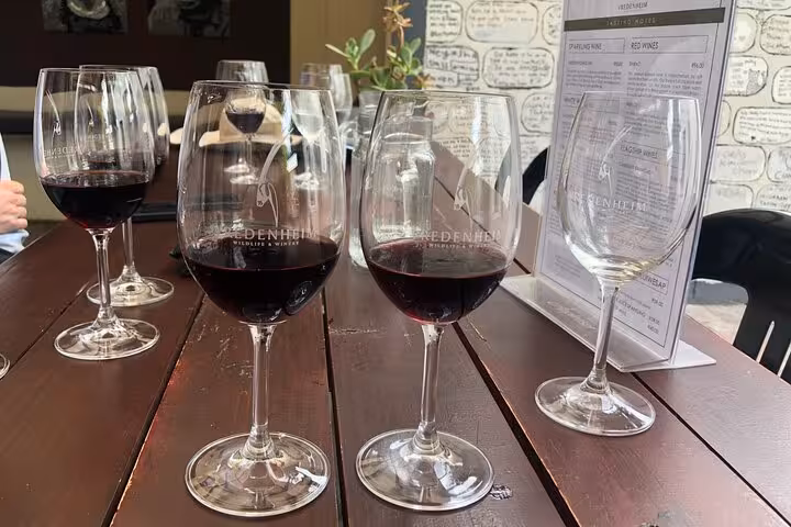 Close-up of red wine glasses on a rustic wooden table, showcasing a tasting experience on the Stellenbosch Wine Tour.