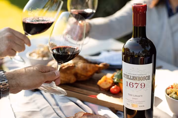 Close-up of Stellenbosch 1679 wine bottle with glasses and gourmet picnic, highlighting a VIP wine tasting experience.