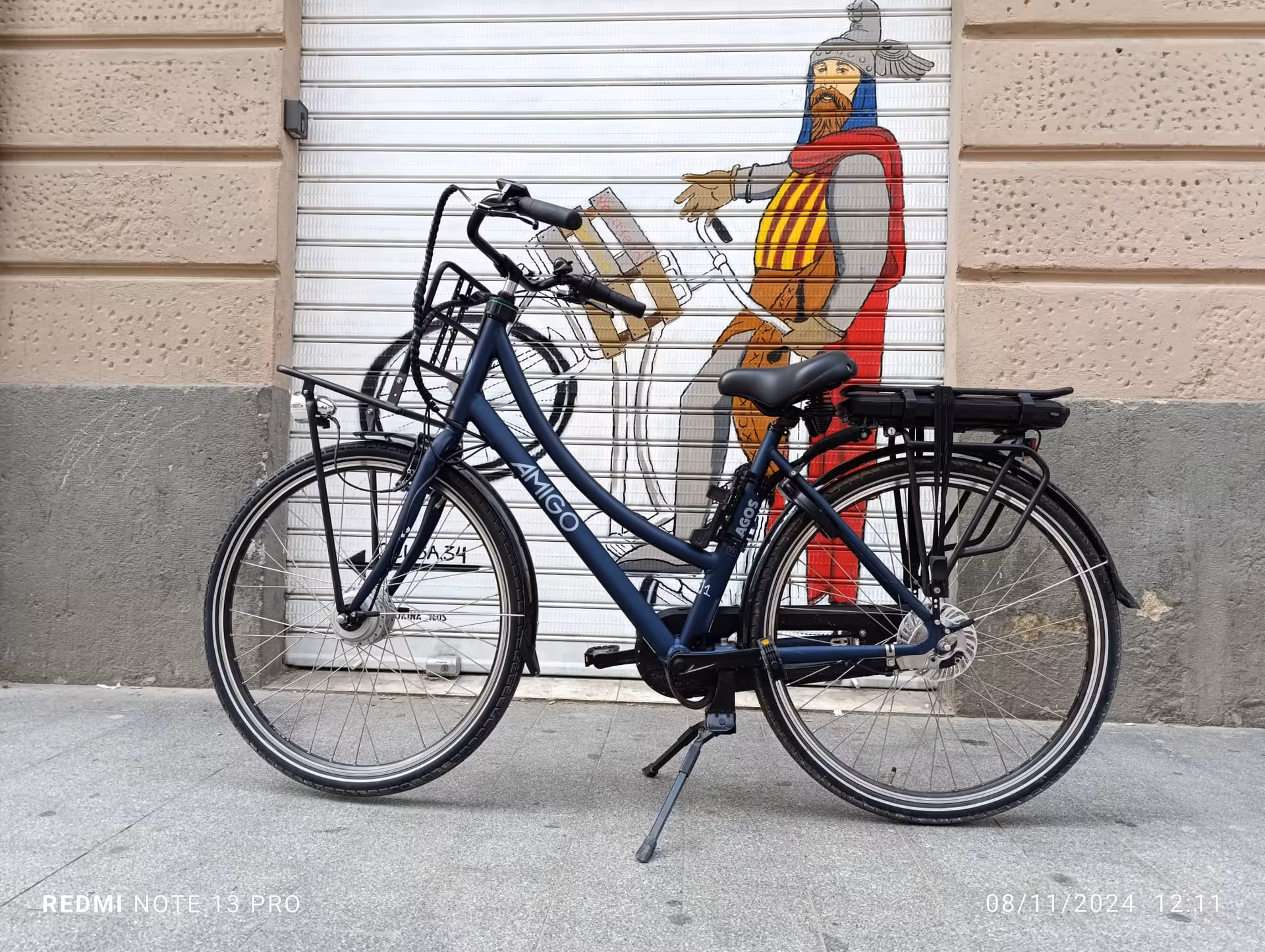 Step-through electric bike rental with rear rack parked by street mural, great for comfortable city exploring