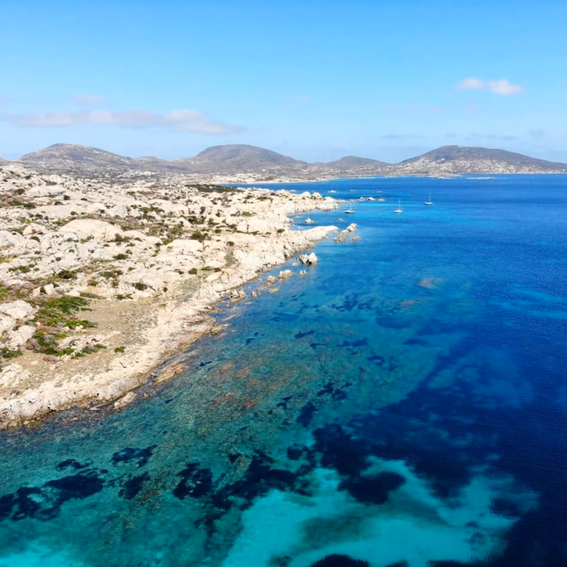 Aerial view of Asinara Island's rugged coastline and clear blue sea, perfect for a Stintino boat trip.