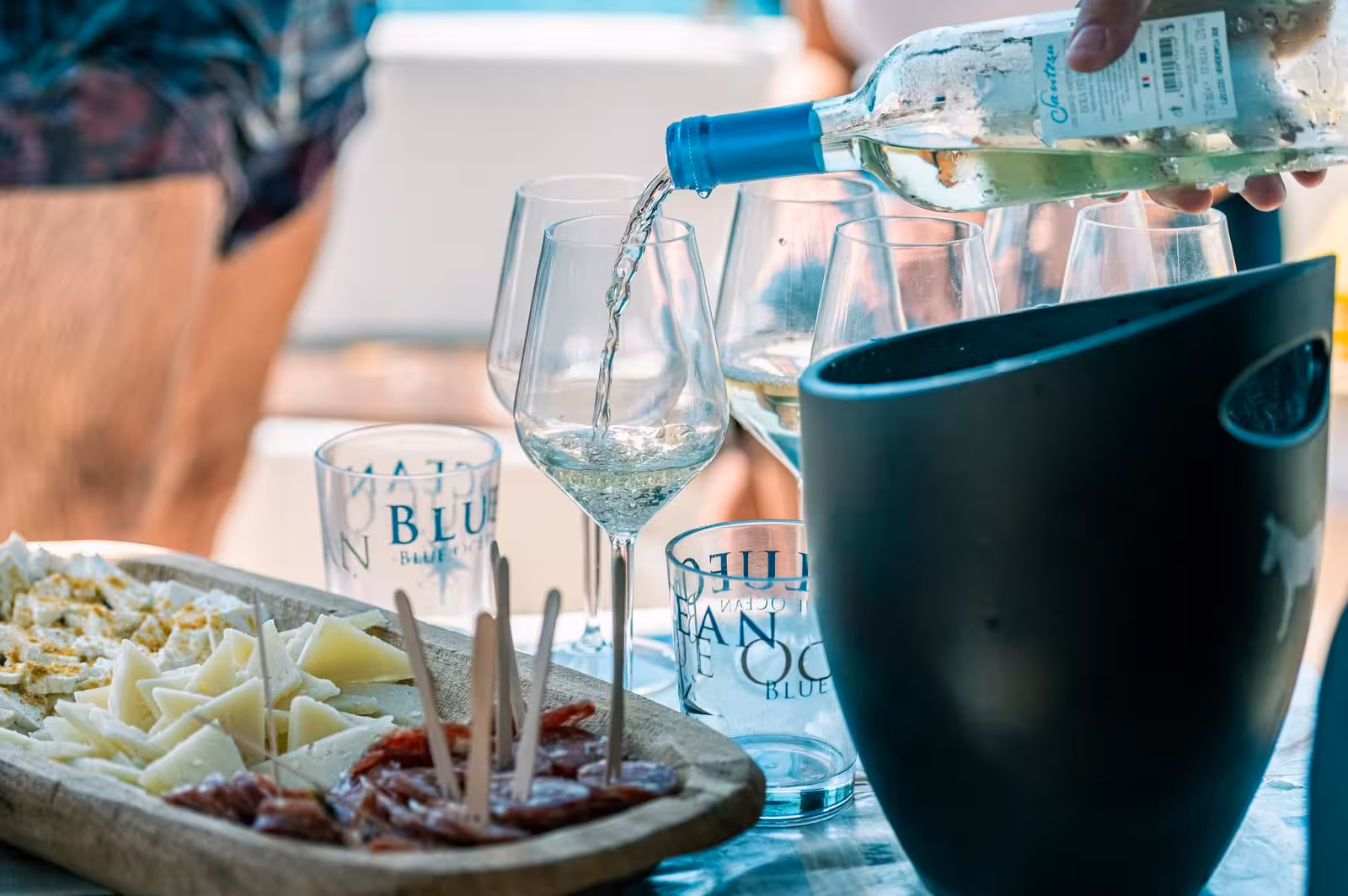 White wine pours into glasses beside a platter of cheese and salami on a sailing trip in Asinara National Park.