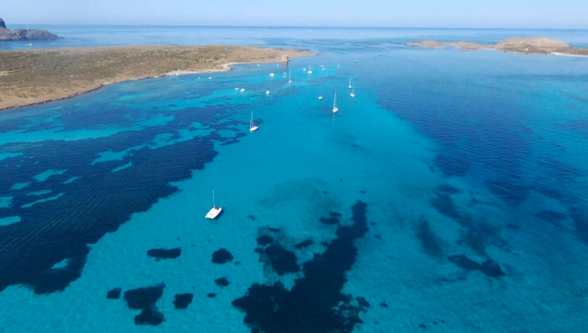 Aerial shot of sailboats dotting the stunning blue waters of the Gulf of Asinara near Stintino.