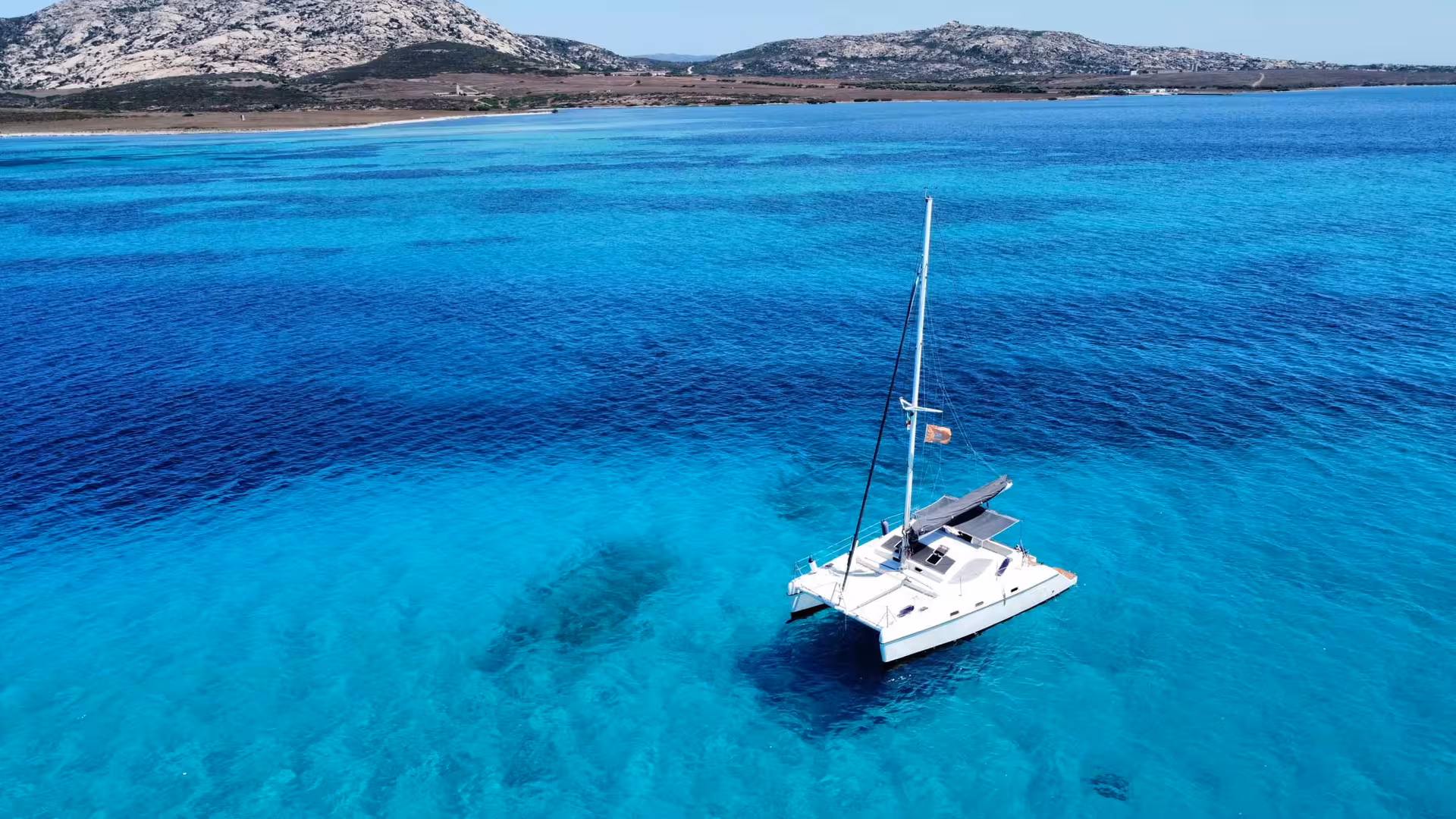 Catamaran anchored in vibrant turquoise waters near Asinara Island, showcasing the stunning coastal scenery of Stintino.