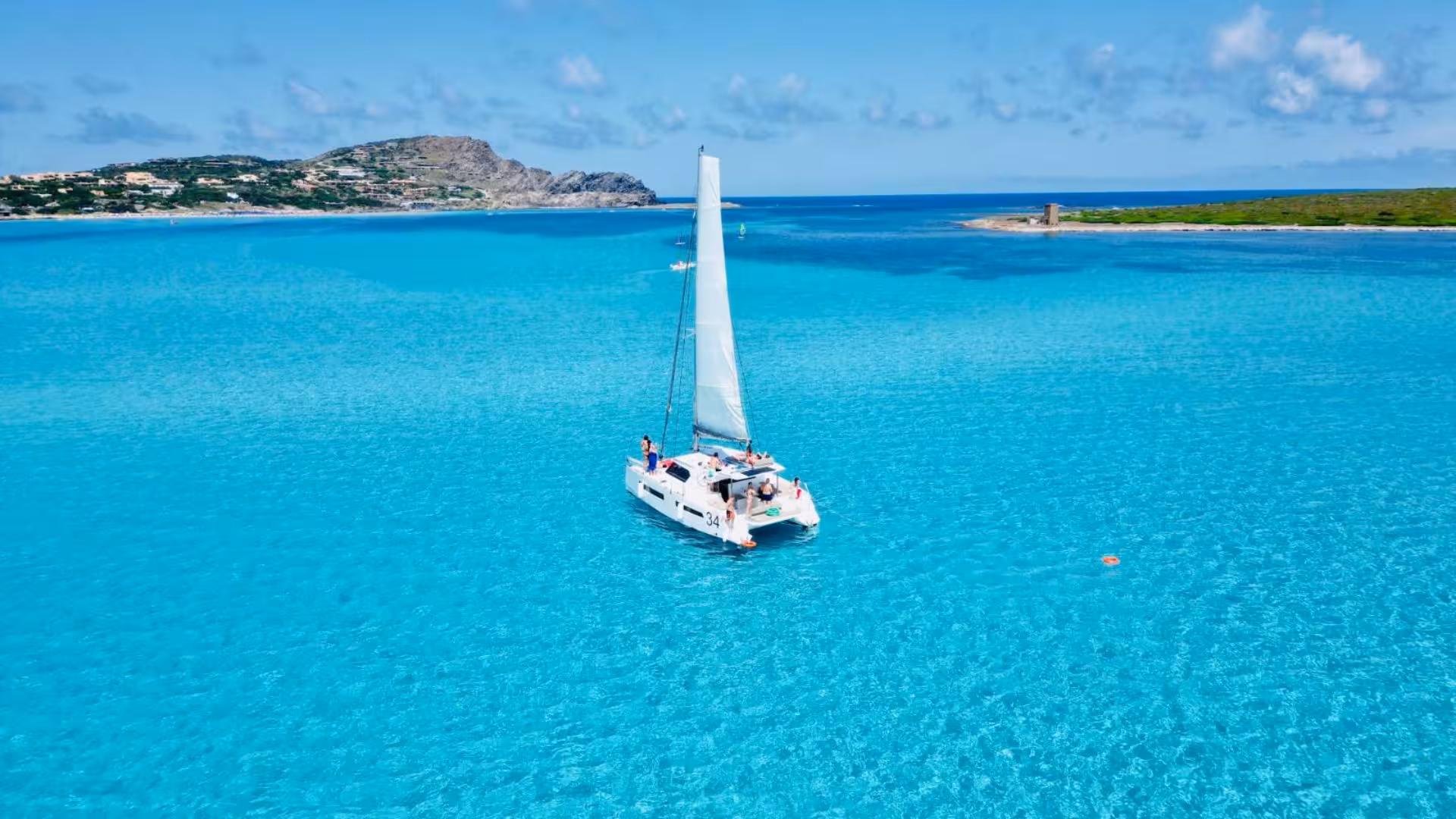 Catamaran sailing in La Pelosa's crystal-clear waters near Stintino, offering a perfect day for relaxation and exploration.